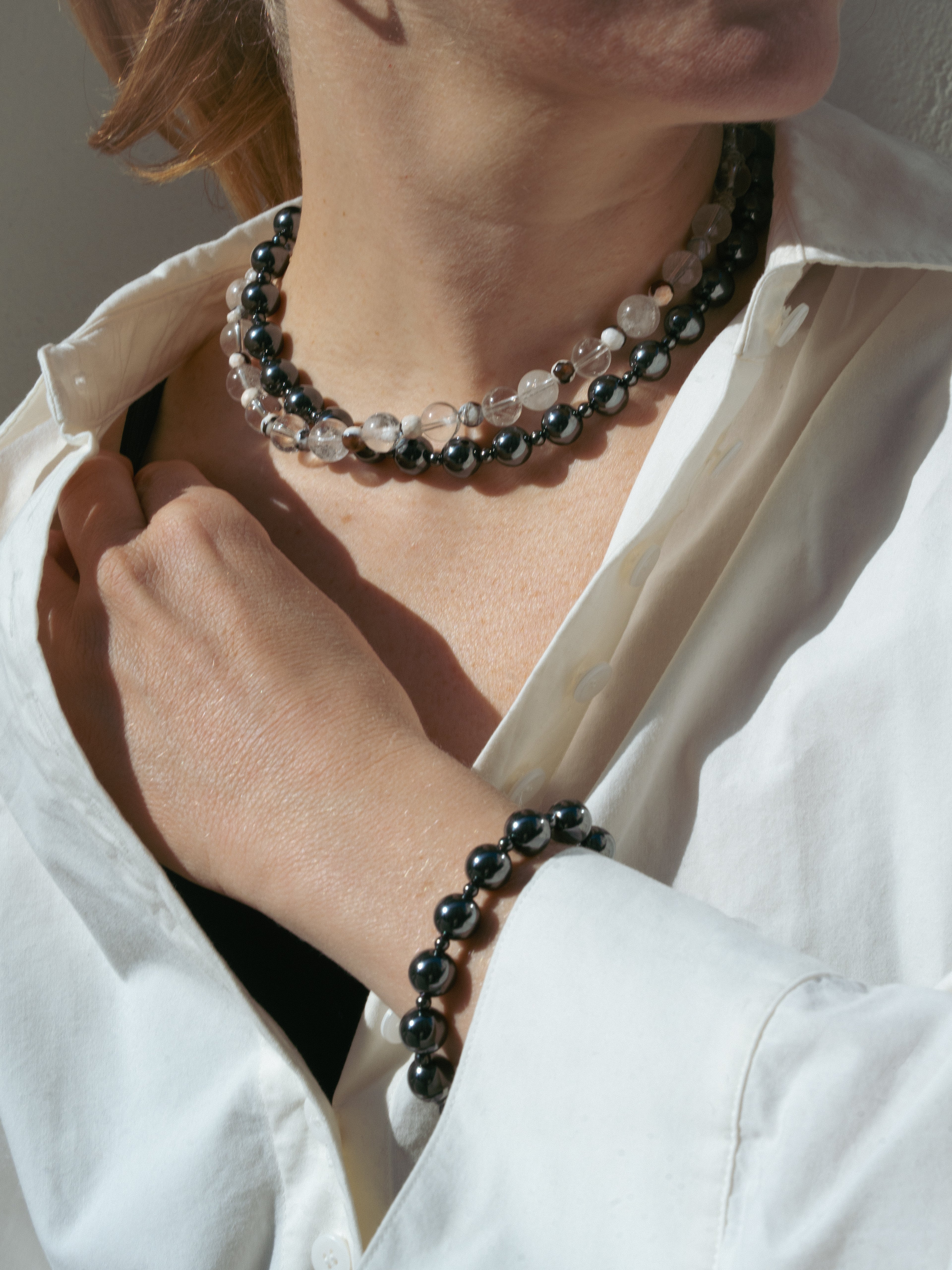 Person wearing a white shirt with a black and crystal beaded necklace and bracelet unisex.