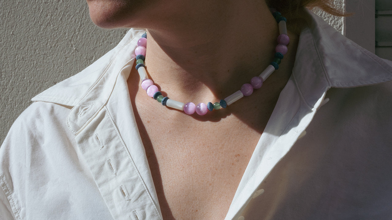 Person wearing a soft multicolored beaded necklace combined with a white blouse