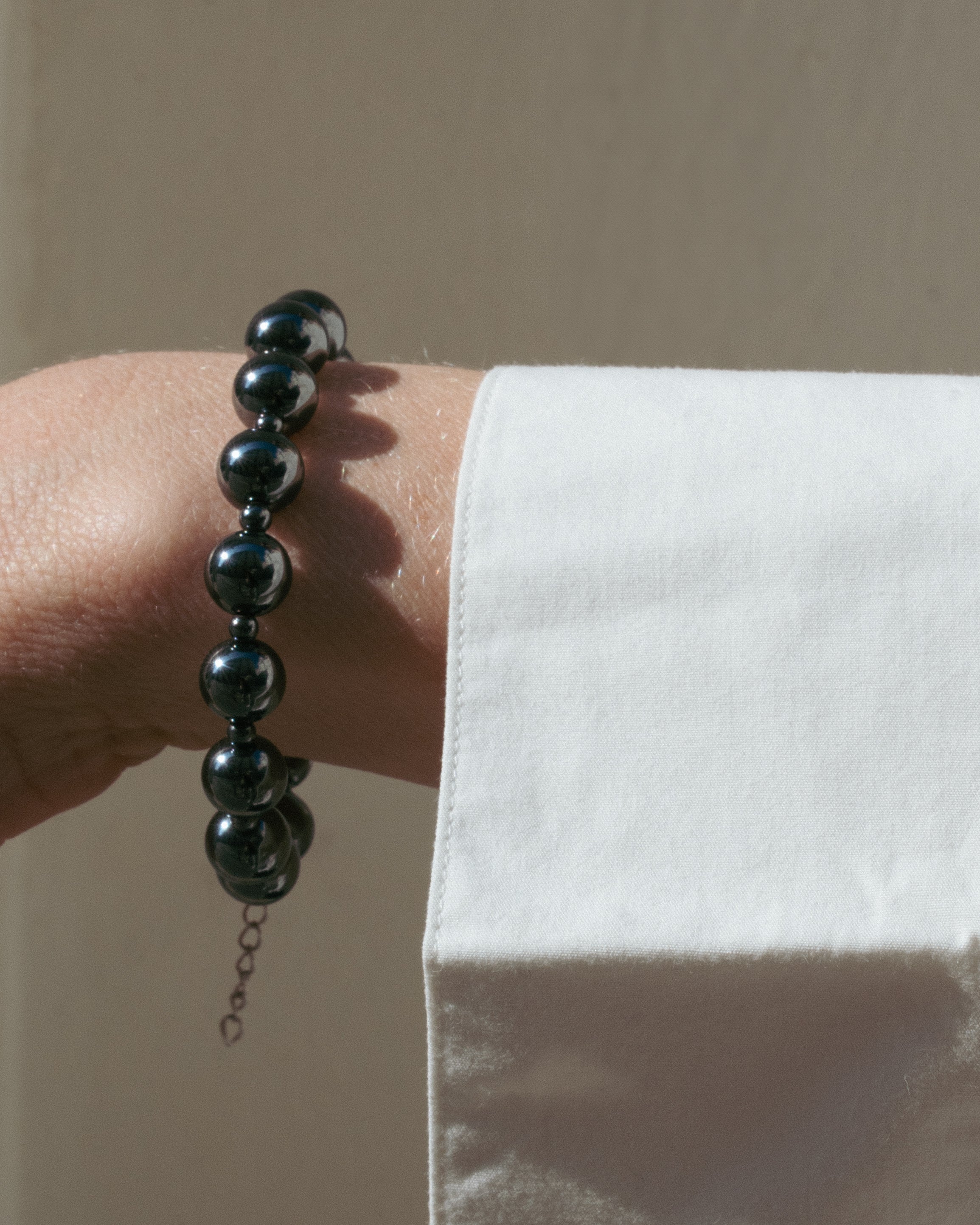 Black beaded bracelet on a wrist with a white blouse sleeve