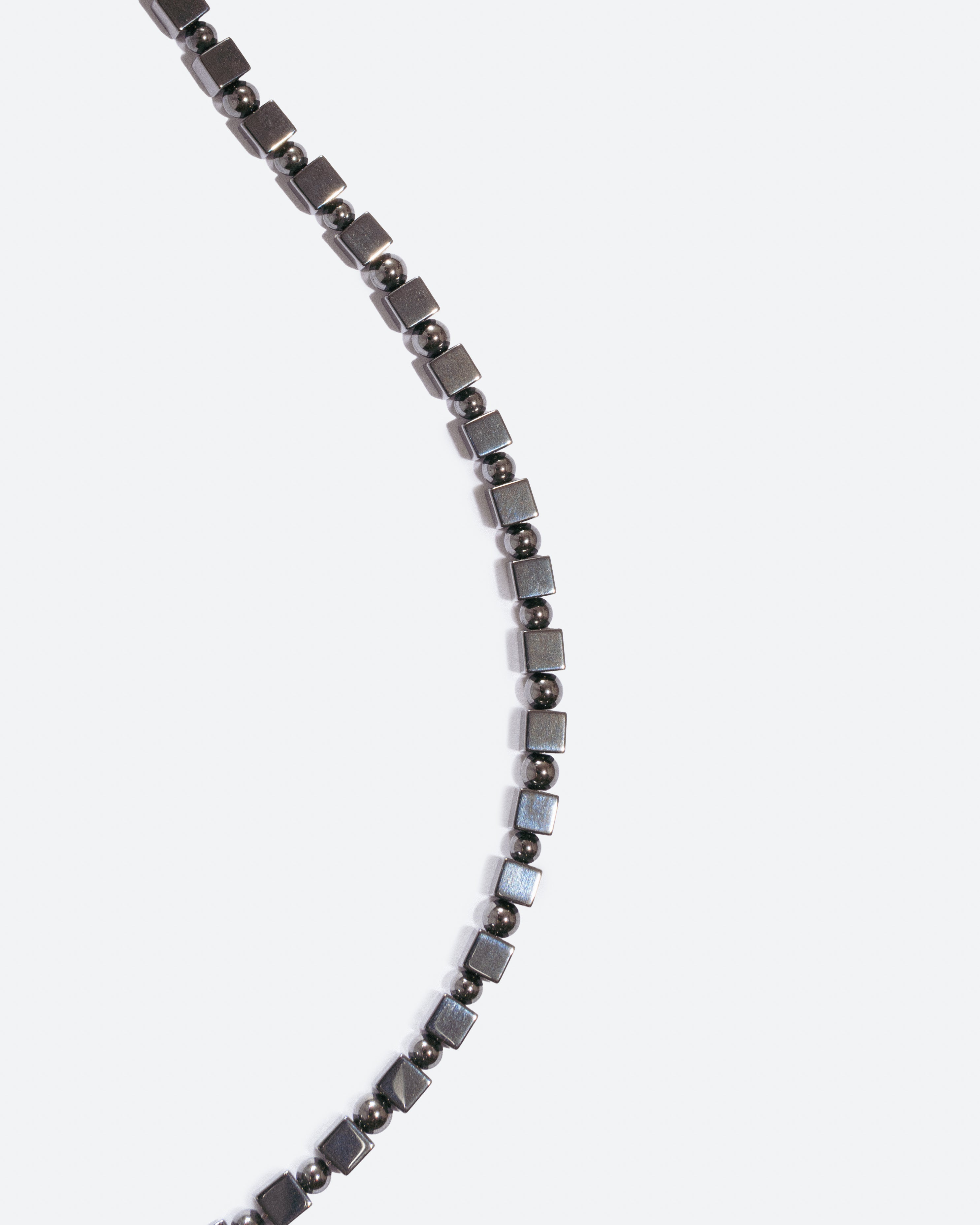 Unisex becklace with small square and round beads on a white background 