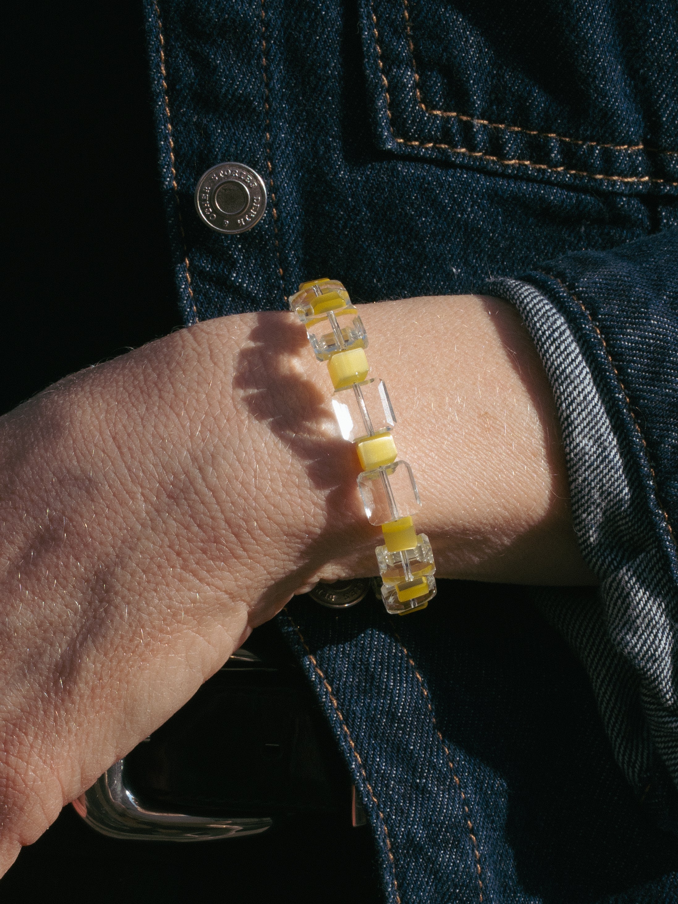 Unisex handmade beaded bracelet with square glass transparent beads and cube cat's eye yellow beads on a handwrist